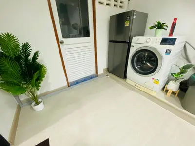 a washing machine in a room with a plant at Cozy Nest Near Downtown in Bangkok