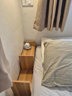 a bed with a wooden nightstand next to a bed sidx sidx sidx at Cat House BKK in Bangkok