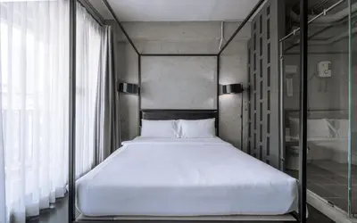 a bedroom with a large bed with a glass wall at The Ex Capital Hotel Bangkok by Dancenter in Bangkok
