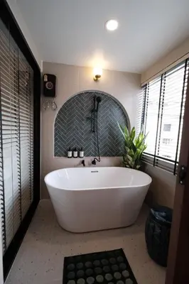 a large white tub in a bathroom with windows at The Shantipan Mandala - Cozy City Retreat 400m from BTS Station in Bangkok