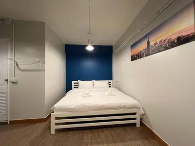 a bedroom with a white bed with a blue wall at Pratunam Family House 2 in Bangkok