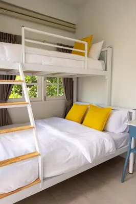 a bedroom with two bunk beds with yellow pillows at Kanal Bangkok Service Residence in Ban Khlong Bang Chak