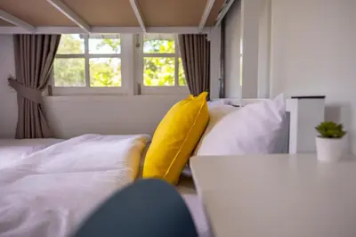 a living room with a couch and a yellow pillow at Kanal Bangkok Service Residence in Ban Khlong Bang Chak
