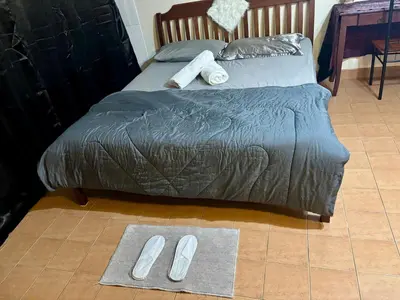 a bed with slippers on the floor in a bedroom at Ally home 12 23 in Thung Si Kan