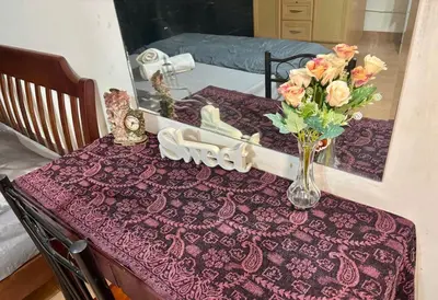 a table with a purple table cloth with a vase of flowers at Ally home 12 23 in Thung Si Kan
