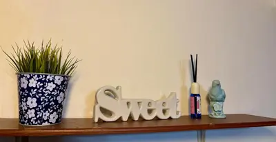 a shelf with a vase and a sign that says swear at Ally home 12 23 in Thung Si Kan