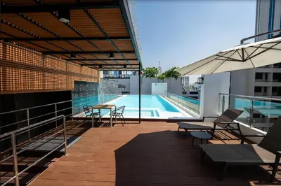 a balcony with a pool and tables and an umbrella at 6th Avenue Sukhumvit BKK Two Bedrooms BTS Asok Nana MRT Sukhumvit in Bangkok