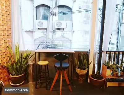 a table and two stools in a room with plants at Friend Nest Bangkok in Bangkok