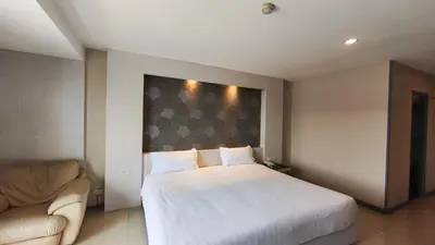 a bedroom with a large white bed and a couch at Avana Residence in Bangna