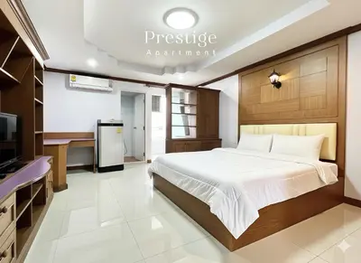 a bedroom with a bed and a desk and a tv at Prestige in Bangna