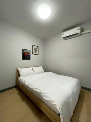 a bedroom with a white bed with a air conditioner at Ananta House in Bang Su