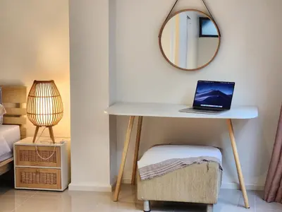 a desk with a laptop on it with a mirror at Be Cozy Silom Modern 2BR 1-min to BTS & MRT in Bangkok