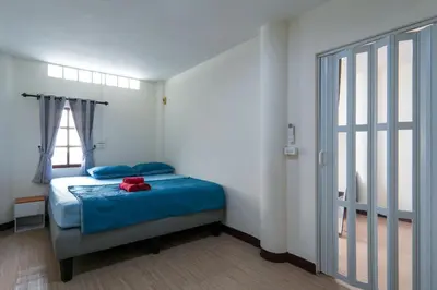 a bedroom with a bed with blue sheets and a window at Baan ABC at 112 Phahonyothin 55 in Bang Khen