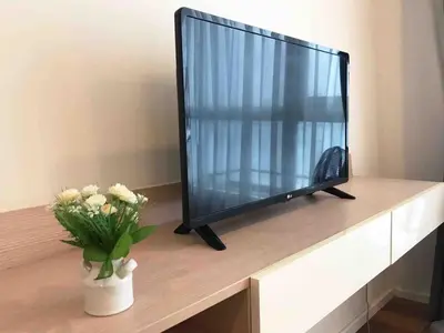 a television sitting on a table with a vase of flowers at Cozy Private Home I Steps to BTS & MRT Sukhumvit Minimum 14 nights in Bangkok