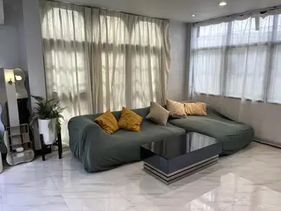 a green couch in a living room with windows at 4BR 12PAX 7min walk to Samitivej Sukhumvit Hospital in Khlong Toei