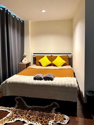 a bedroom with a bed with yellow pillows and a leopard rug at 4BR 10PAX Ensuite Near EmQuartier Emporium Emsphere in Khlong Toei