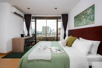 a hotel room with a bed and a desk and window at KingBed|BTS&Park»5min|ParkView|Gym|Washer|FastWiFi in Khlong Toei