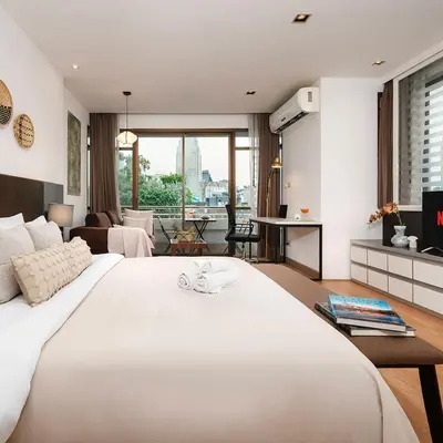 a bedroom with a large white bed and a living room at Quiet Asoke/Nana BTS Retreat w/ Skyline & Gym/Park in Khlong Toei