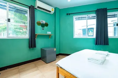 a green room with a bed and two windows at xxGO INN The Giant Swing - โกอินน เสาชิงช้า in Bangkok