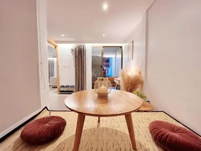 a living room with a wooden table and red ottoman at MRT-Accessible & Delightful Family Hub! in Bangkok