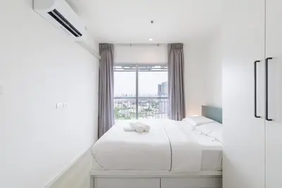 a white bedroom with a bed and a window at Downtown Spacious Luxury Condo BKK- 5 mins BTS! in Bangkok