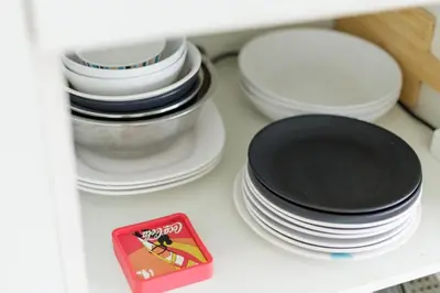 a pile of plates and bowls and a red box on a shelf at Downtown Spacious Luxury Condo BKK- 5 mins BTS! in Bangkok