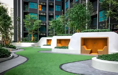 a building with a green lawn in front of a building at Life asoke rama 9 in Bangkok