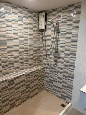 a shower in a bathroom with a tile wall at Ni Haus, cozy place for 4 people in Bangkok