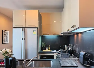 a kitchen with a sink and a refrigerator at Near BTS - High Floor - Pool and Gym - Sontana in Bangkok