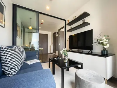 a living room with a blue couch and a tv at Near BTS - High-Floor - Rooftop Pool - Sontana in Bangkok