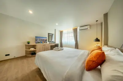 a bedroom with a white bed with an orange pillow at Ralph Poshtel Sukhumvit in Bangkok