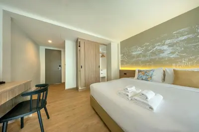 a bedroom with a large white bed with a desk at Ralph Poshtel Sukhumvit in Bangkok