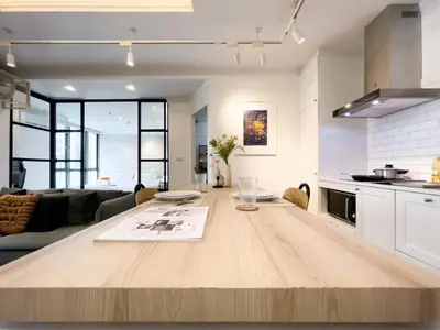 a kitchen and living room with a wooden table at Prime Chidlom 50sqm l Large Kitchen l Walk to BTS l Wifi in Bangkok