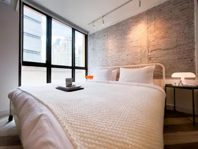 a bedroom with a large bed with a brick wall at Prime Chidlom 50sqm l Large Kitchen l Walk to BTS l Wifi in Bangkok