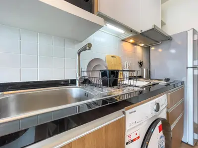 a kitchen with a sink and a washing machine at Prime Sukhumvit Living - BTS Phrom Phong - Ultra Fast WiFi in Bangkok