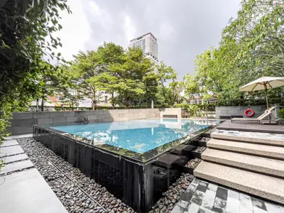 an infinity pool with stairs and an umbrella at Prime Sukhumvit Living - BTS Phrom Phong - Ultra Fast WiFi in Bangkok
