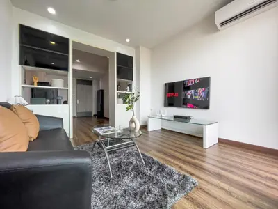 a living room with a black couch and a tv at Downtown Stay 65 sqm - Ultra-WiFi - BTS Ratchathewi in Bangkok