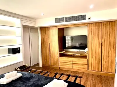 a bedroom with a large entertainment center with a flat screen tv at Thong Lo 3BR Home 75in SmartTV Netflix - Quiet Home in the City Center in Bangkok