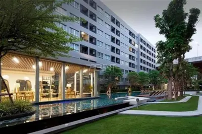 a large building with a swimming pool in front of it at Elio Sukhumvit 64 BTS Punnawithi in Amphoe Phra Khanong