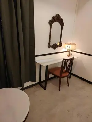 a table with a lamp and a chair in a room at XX The Character Yaowarat-ตรอกข้าวสาร in Samphanthawong