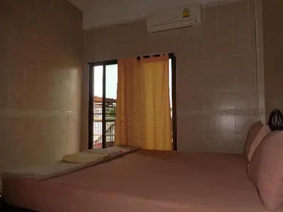 a room with a large bed with a window at At Home Guest House in Bangkok