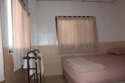 a small room with a bed and a window at At Home Guest House in Bangkok
