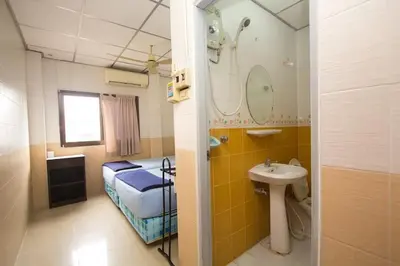a small bathroom with a bed and a sink at At Home Guest House in Bangkok