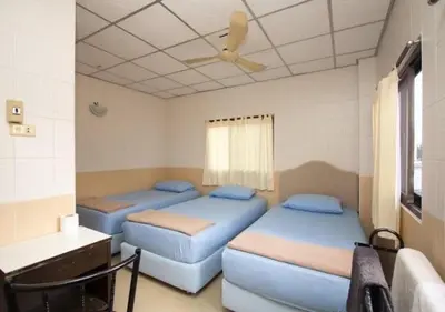 two beds in a room with a ceiling fan at At Home Guest House in Bangkok