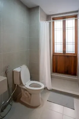 a bathroom with a toilet and a window at Crownex Studio Deluxe in Bangkok
