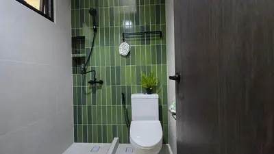 a green tiled bathroom with a toilet and a shower at TownHouse near Central Ladprao with bathtub in Bangkok