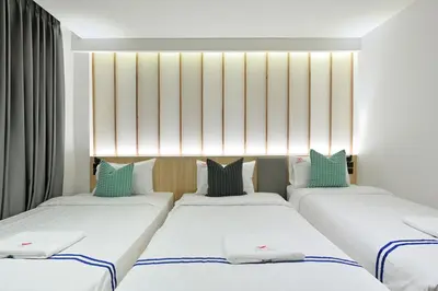 three beds in a room with white and blue pillows at Tori primo hotel in Bangkok