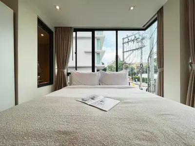 a bedroom with a large bed with a window at Vibe Sukhumvit 61 l Ultra WIFI l Walk to BTS Thonglor or Ekkamai in Bangkok