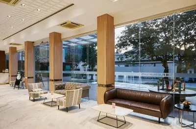 a lobby with couches and tables and large windows at The Platinum Suites Bangkok by Dancenter in Bangkok
