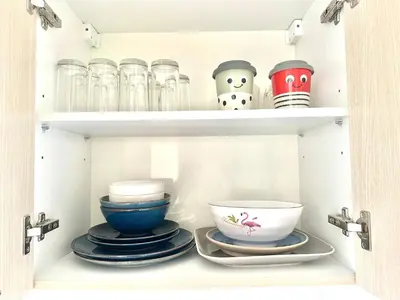 a cupboard with plates and bowls and glasses at Cozy City Retreat in Ekkamai in Bangkok